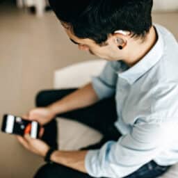 Young man with a hearing aid using his smartphone.