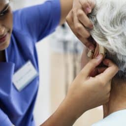 Senior woman being fitted for a hearing aid by a medical professional.