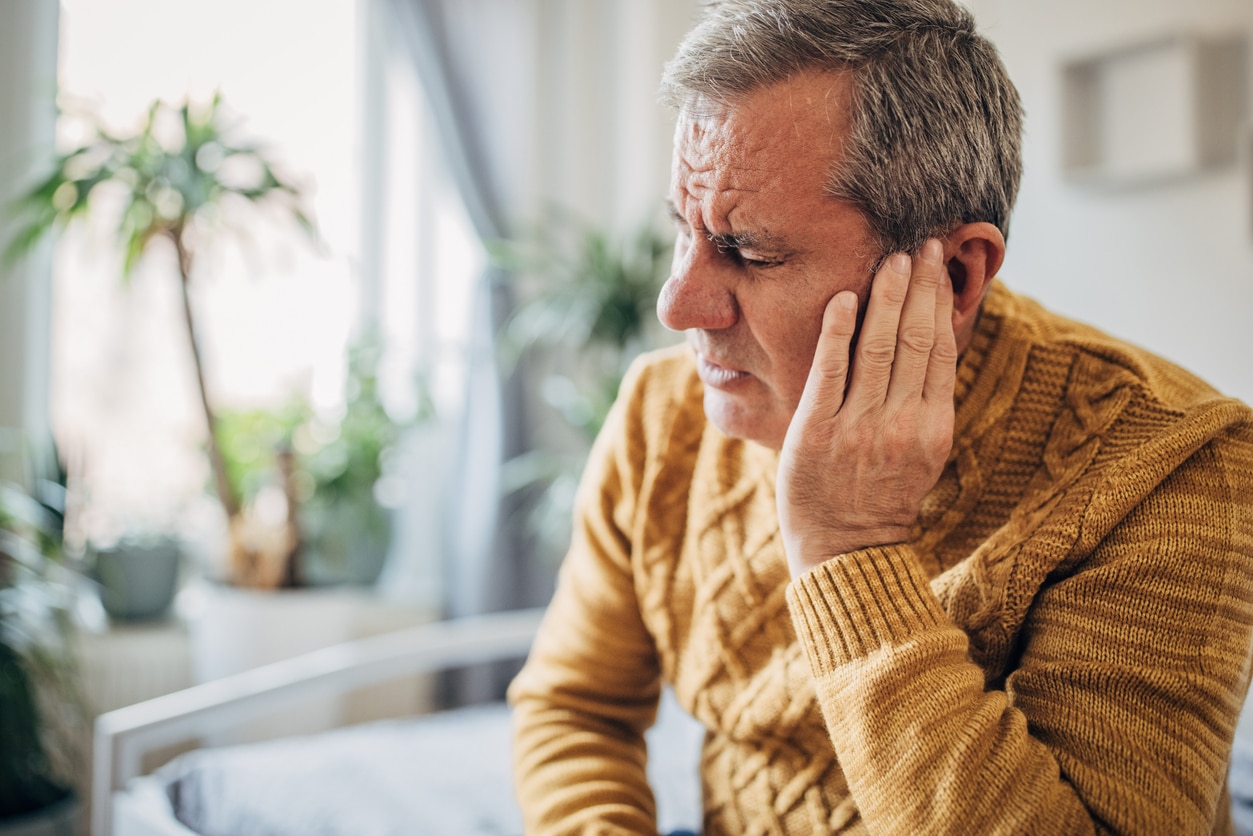 Senior man experiencing ear discomfort touching his ear