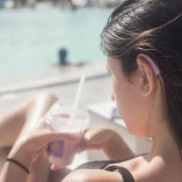 Woman sitting by the pool with a hearing aid in her ear