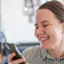 Woman with hearing aid smiling at her phone