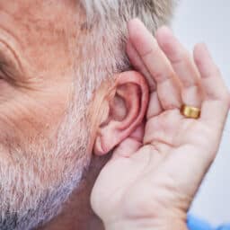 Man cups ear to indicate hearing loss