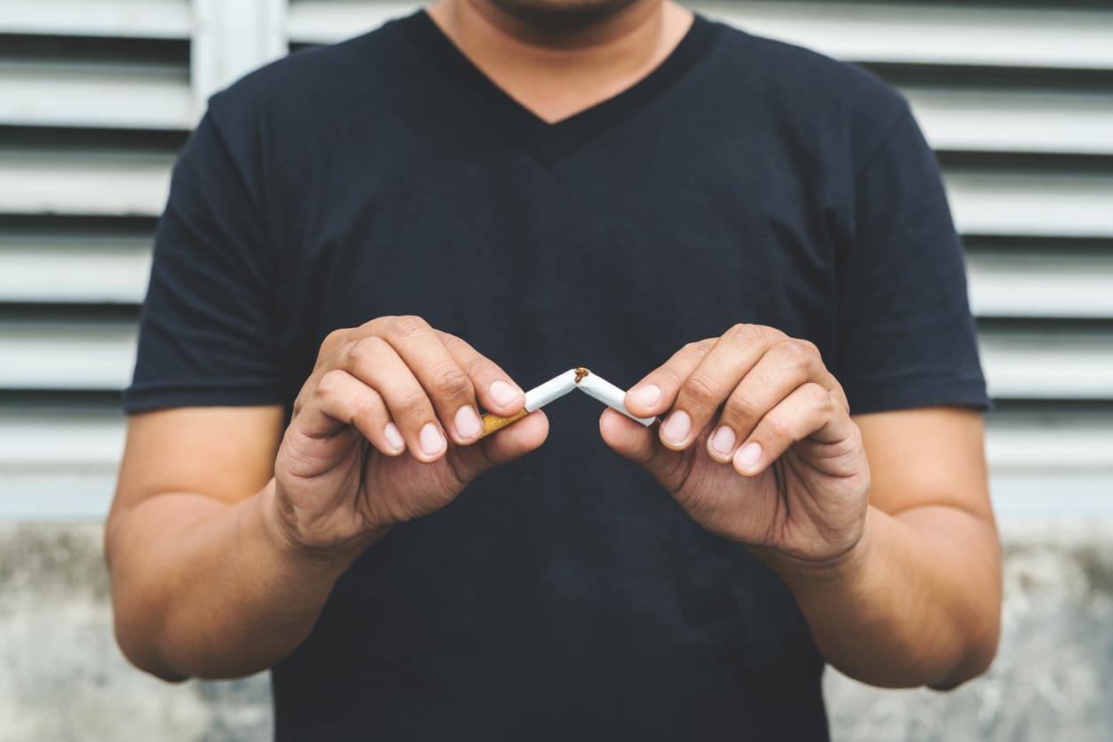 Man breaking a cigarette in half.