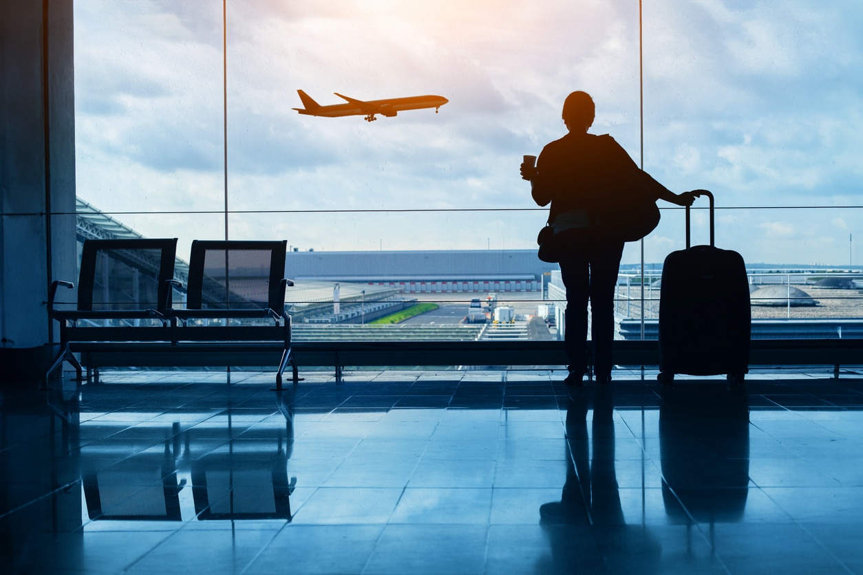 Woman in the airport watching a plane fly by.