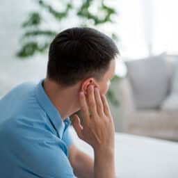 Man with tinnitus holding his ear