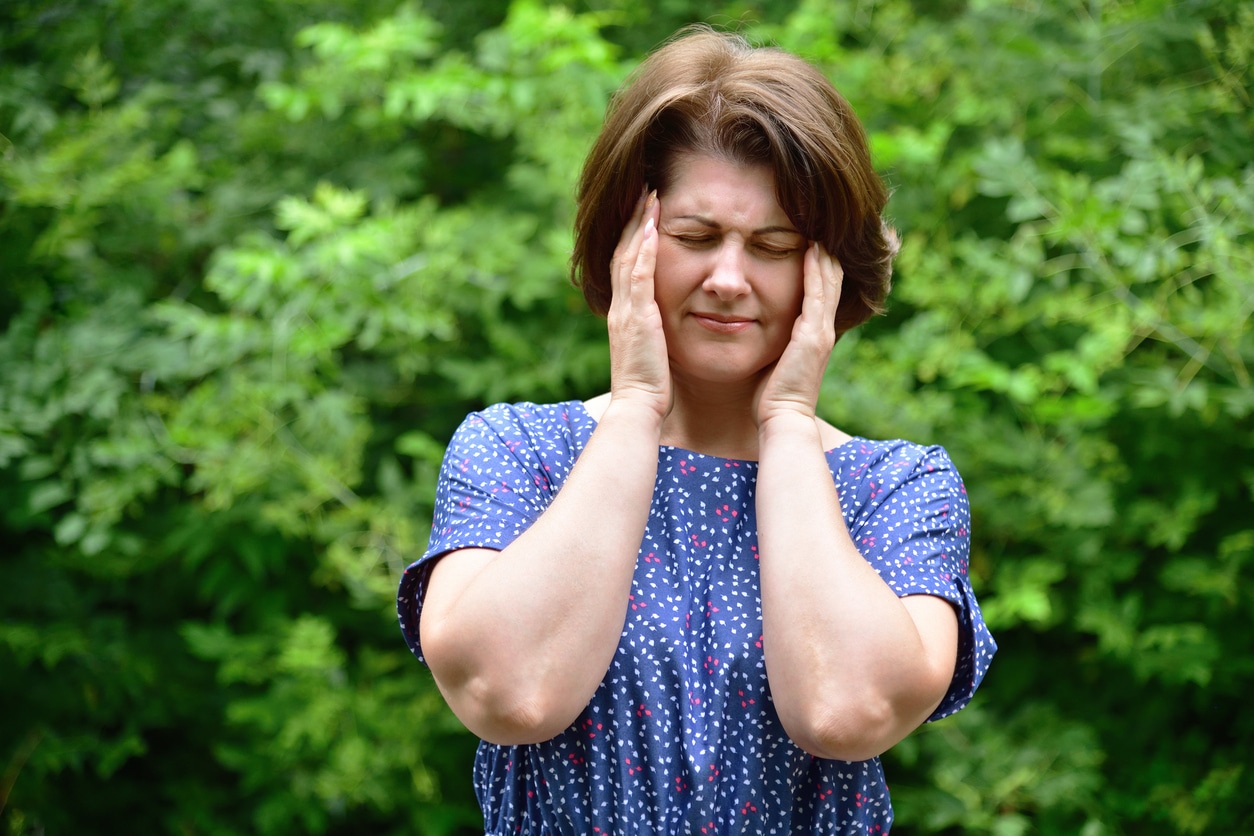 Woman holds her hands to her temples.