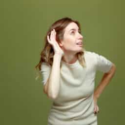 Young woman with her hand to her ear trying to hear