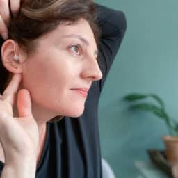 Smiling woman showing her properly placed hearing aid